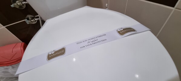 Un inodoro blanco con una etiqueta que indica que fue sanitizado por precaución.