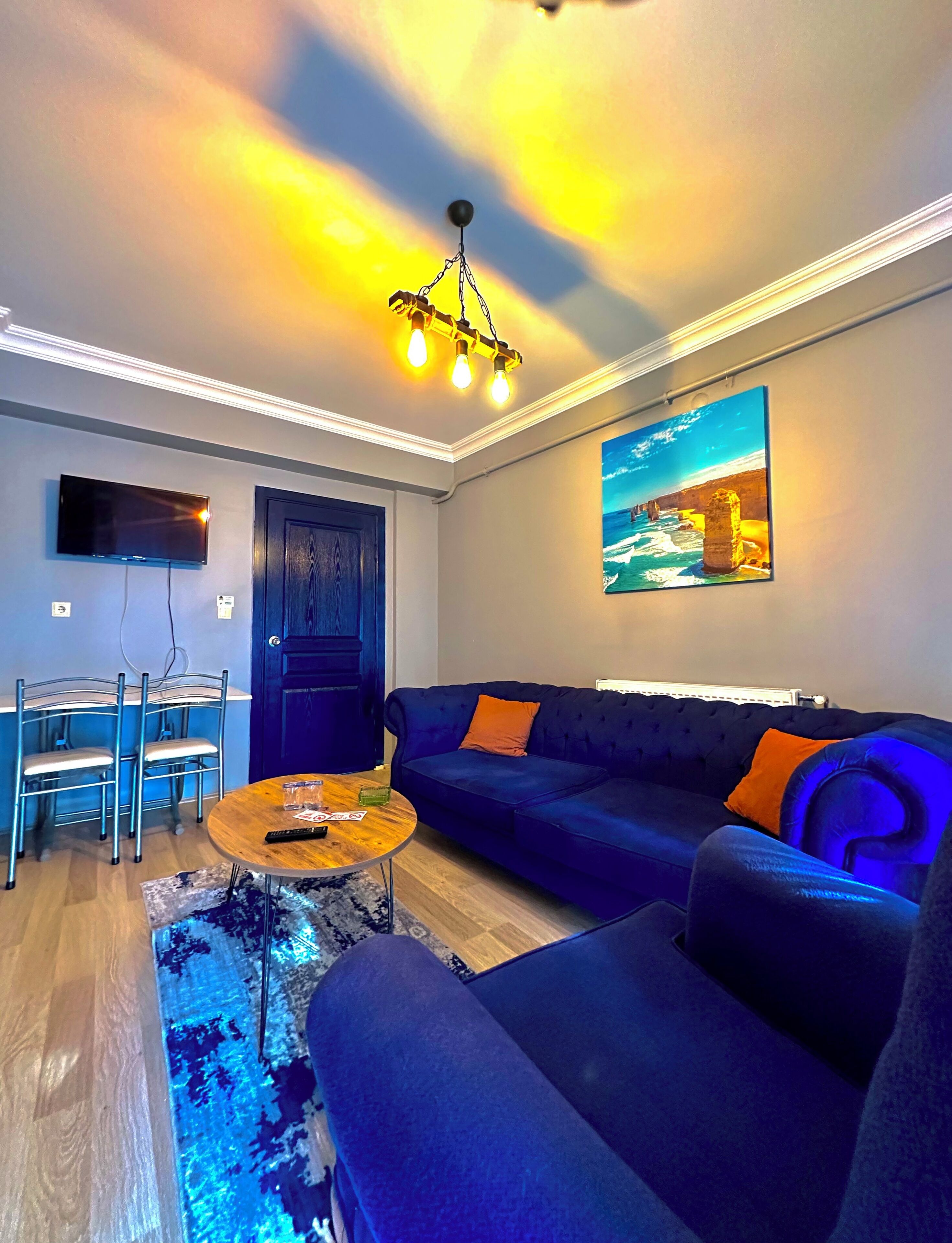 Una sala de estar moderna con un sofá azul, una mesa de centro de madera y un televisor montado en la pared.