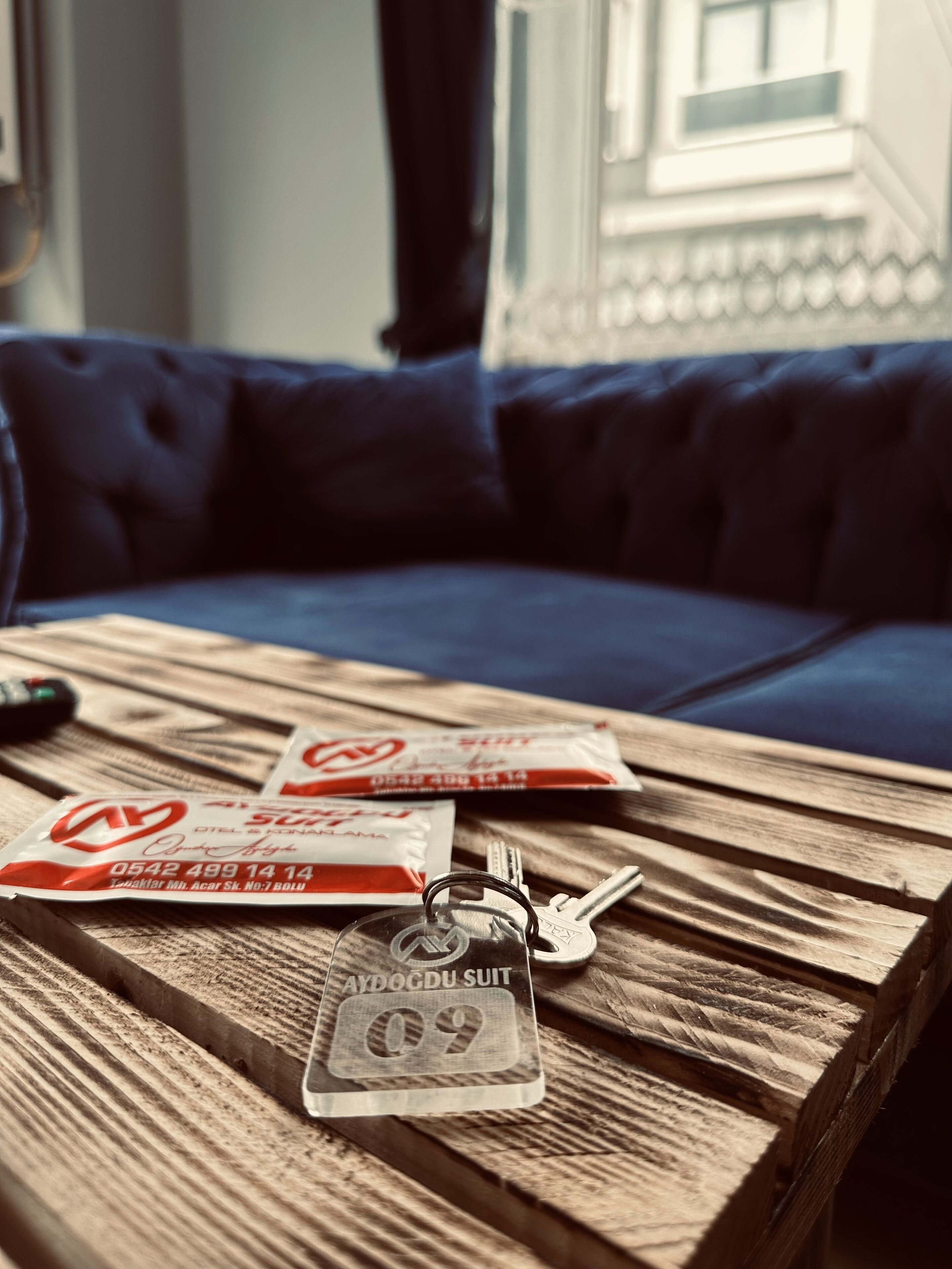 A wooden table with a keychain and a packet of cigarettes.