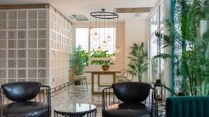 Un intérieur moderne comprenant un coin salon, une plante décorative et une fenêtre laissant entrer la lumière naturelle.