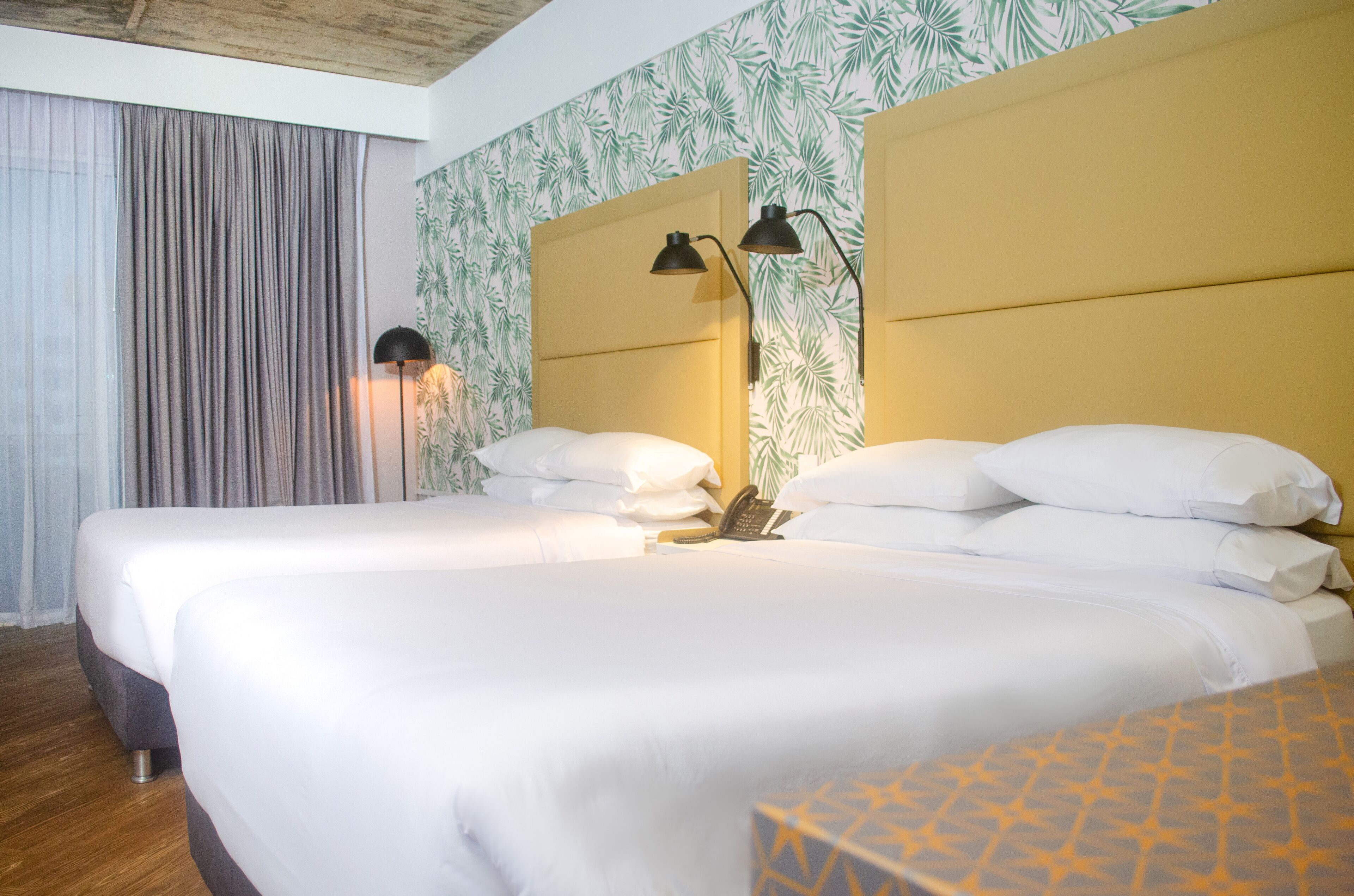 A hotel room with two beds, a telephone, and a lamp.