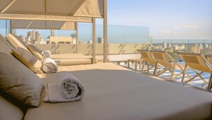 Une chambre d’hôtel située dans un immeuble de grande hauteur, avec un lit, des fauteuils et une vue sur la ville.