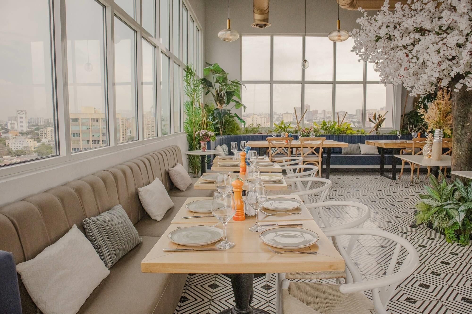A modern dining area with a city view, large windows, and a mix of seating options including a sofa and tables.