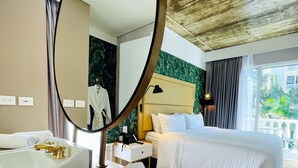 Une chambre d’hôtel avec un grand miroir rond, une baignoire, un lit et une table de chevet avec une lampe.