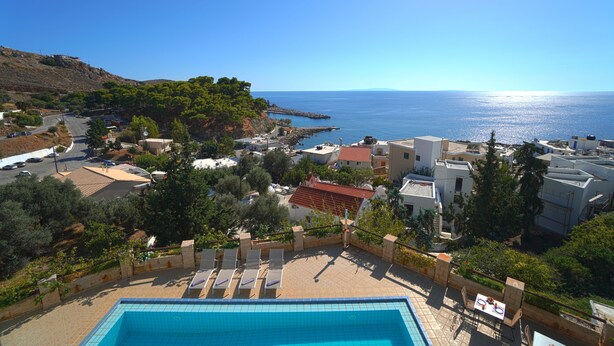 A pool area with lounge chairs and a view of the sea. - Sfakian Horizon (Sfakia)