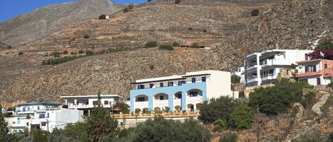 A hillside with buildings, including a blue and white structure with multiple balconies.