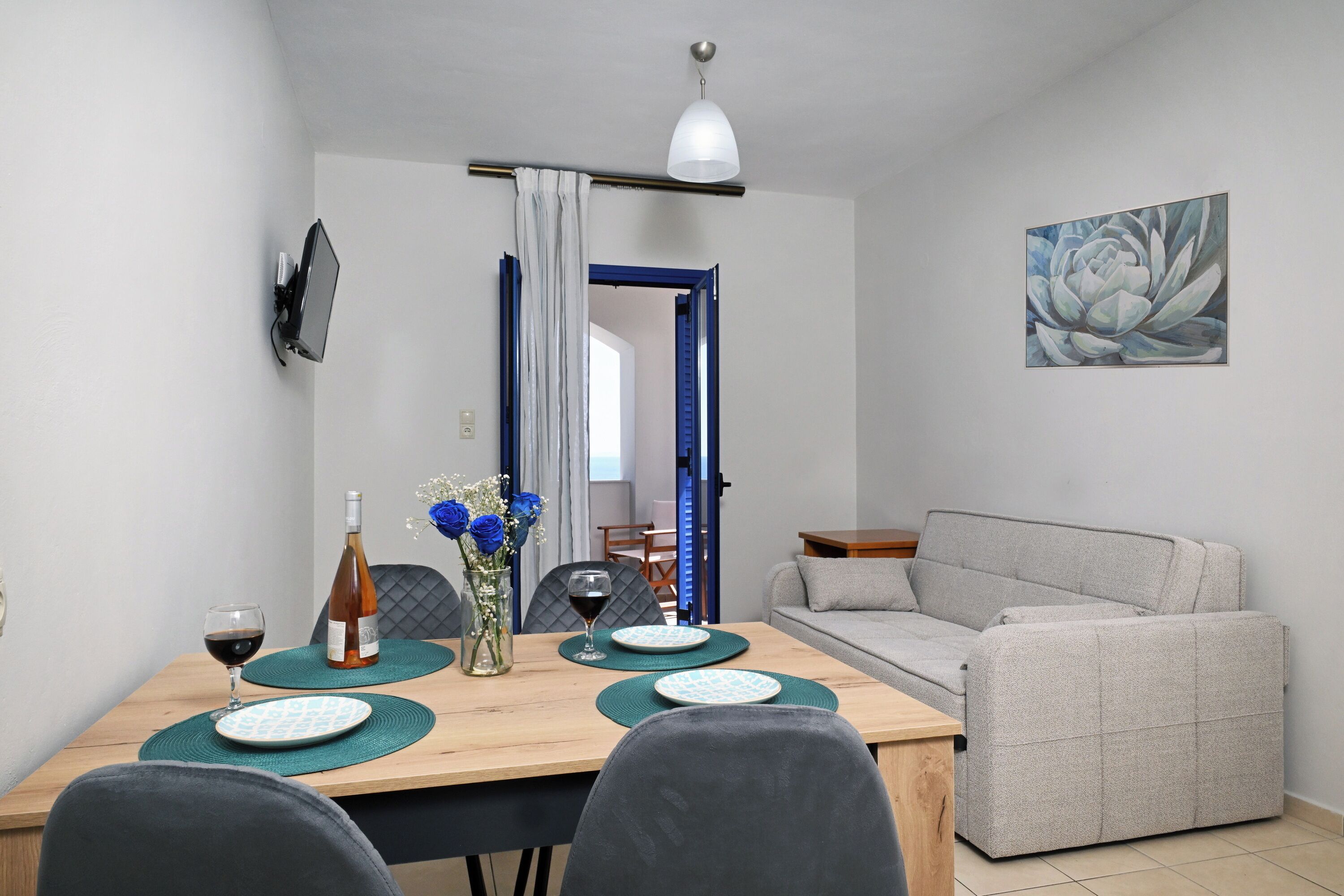 Een eethoek met een tafel, stoelen, een bank en een schilderij aan de muur.