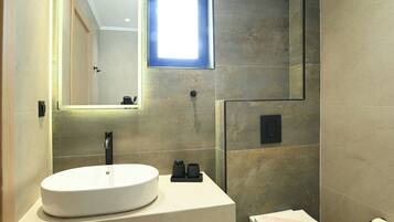 A modern bathroom with a large mirror, a white sink, and a toilet.
