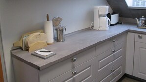 Een keuken met witte kastjes, een koffiezetapparaat en een raam met uitzicht.