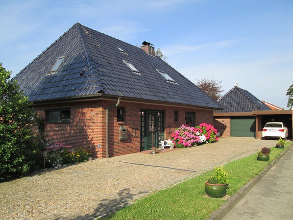 A brick house with a sloped roof, a garage, and a gravel driveway. - Vacation apartment Hahneburg in Simonsberg (Simonsberg OT. Finkhaus)