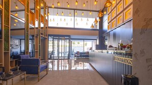A modern hotel reception area with a glass door entrance, wooden shelving, and a reception desk. - Methis Hotel (Izmir)