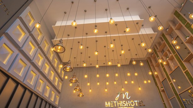 A hotel interior with hanging pendant lights, geometric wall designs, and a visible sign reading "METHISHOTA." - Methis Hotel (Izmir)