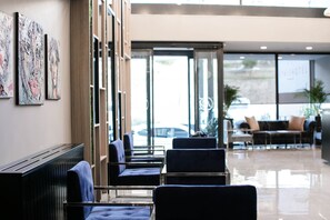 Eine moderne Hotelhalle mit Sitzbereichen, Kunstwerken an den Wänden und Blick ins Freie.
