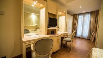Habitación de hotel con escritorio, dos sillas, televisor y cama.