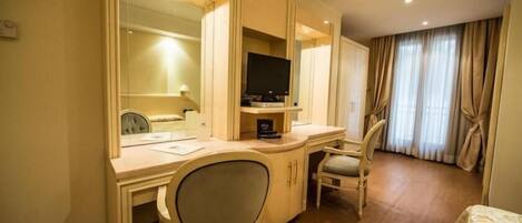 Habitación de hotel con escritorio, dos sillas, televisor y cama.
