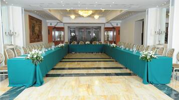 Un salón de conferencias con una larga mesa, sillas y una araña.