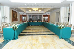 Un salón de conferencias con una larga mesa, sillas y una araña.