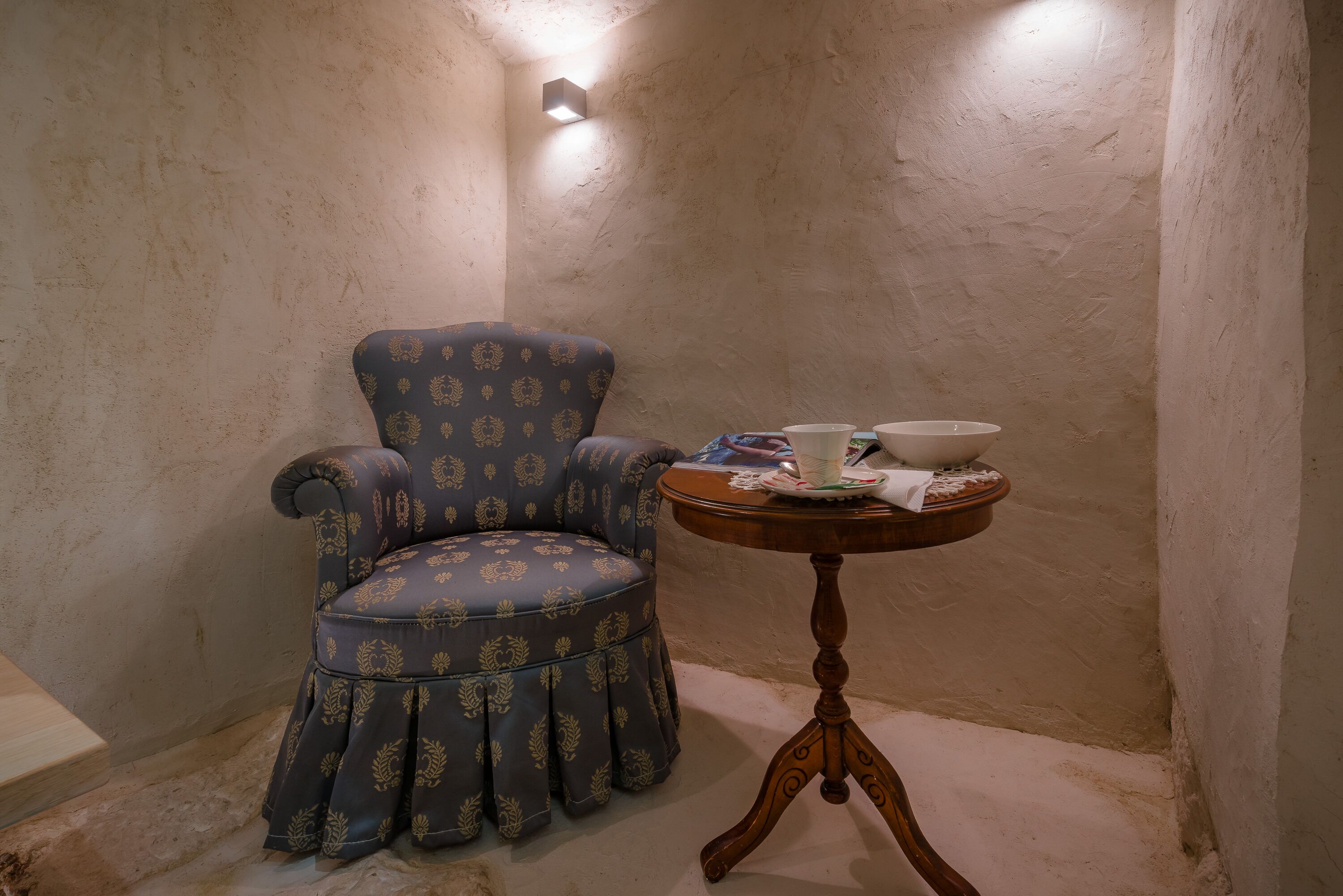 Een hoekzaak met een gestreept fauteuil en een klein houten tafeltje met een kop en schotel.