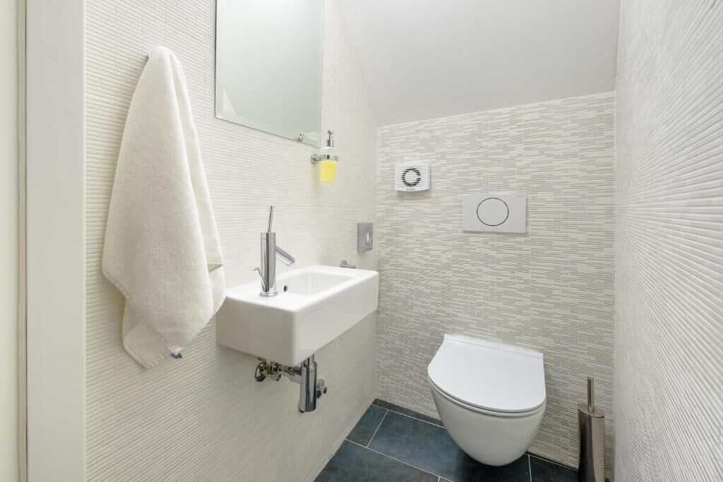Et stilfuldt badeværelse med hvid vask, spejl og toilet.