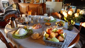 A breakfast table set with various dishes, a vase of flowers, and a brick wall in the background. - B&B La Chrysalide (Mons)