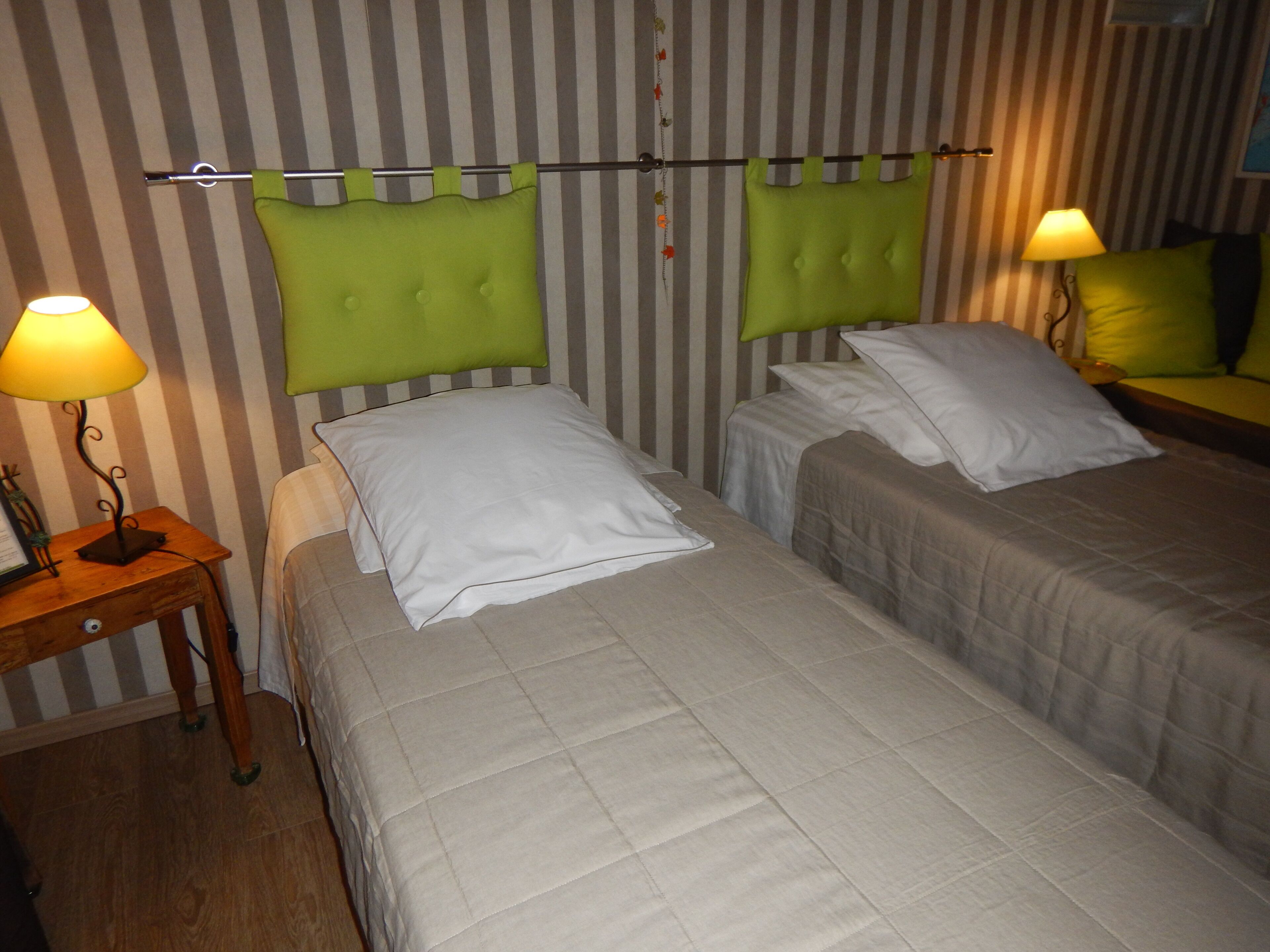 A hotel room with two beds, striped wallpaper, and bedside lamps.