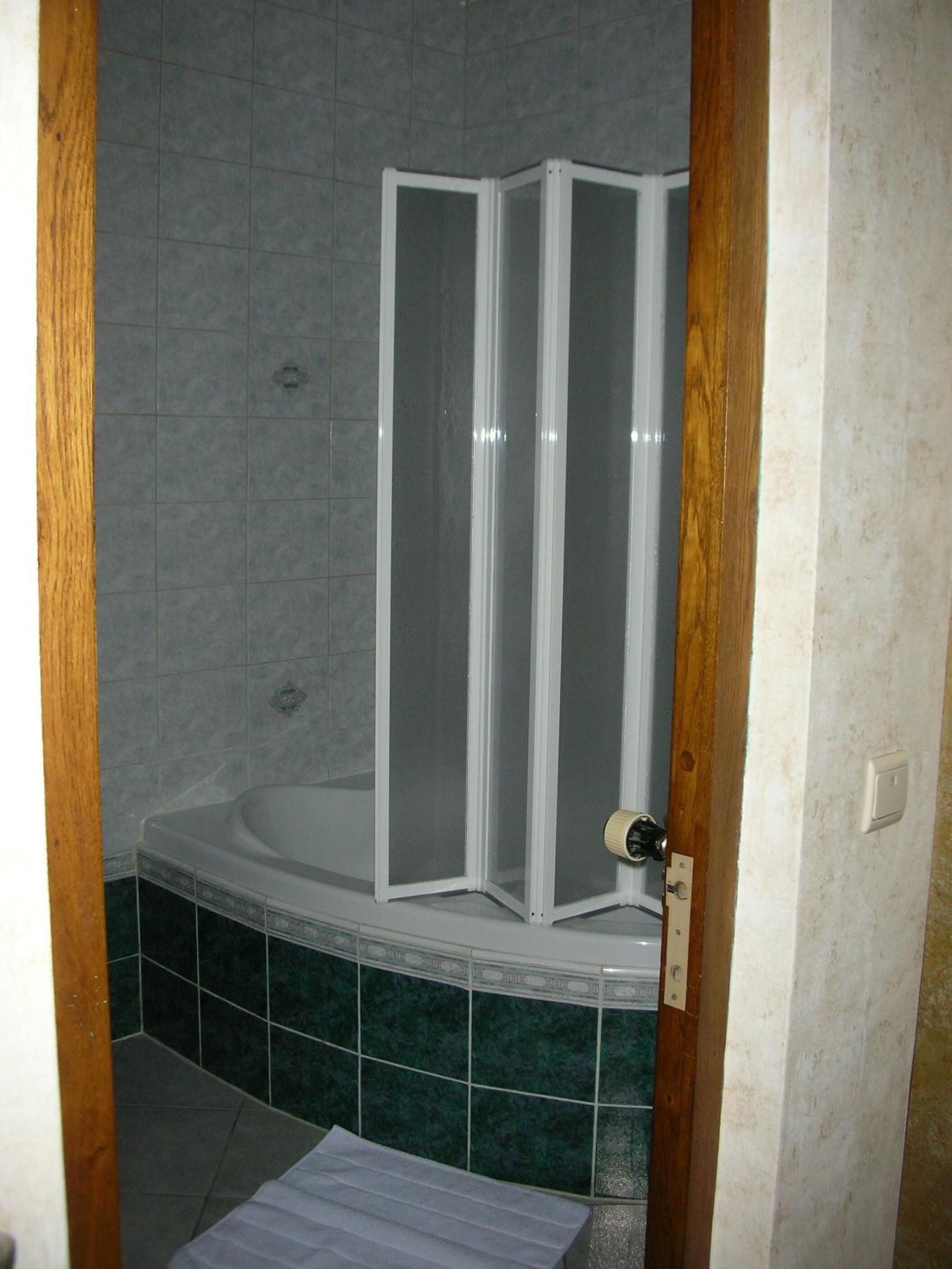 Uma casa de banho com cabine de duche, banheira e chão em mosaico.