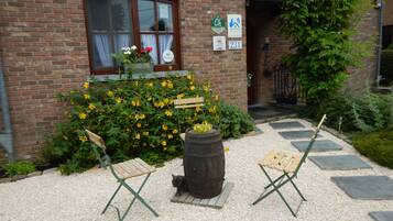 Sit and unwind in this charming outdoor seating area adjacent to the building, featuring a planter with flowers and comfortable seating.