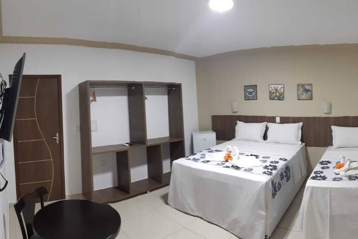 Une chambre d’hôtel avec deux lits, un bureau, une chaise, une armoire et un téléviseur.