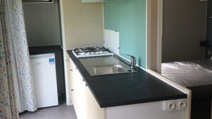 A compact kitchen with a gas stove, sink, and a microwave.