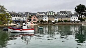 A harbor with boats, a building with a pointed roof, and a stone wall.