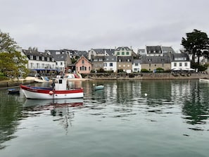 A harbor with boats, a building with a pointed roof, and a stone wall.