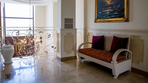 Un'accogliente hall d'hotel con un divano bianco, un lampadario, un quadro e una segnaletica con indicazioni.