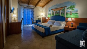 Una camera d'albergo con un letto, una scrivania, una sedia, un comodino e un quadro appeso al muro.