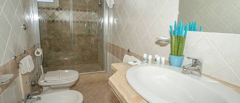 Un baño con ducha, inodoro, bidé y lavamanos.