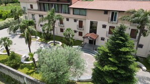 Un hotel con un cortile centrale, palme e un tetto in tegole.