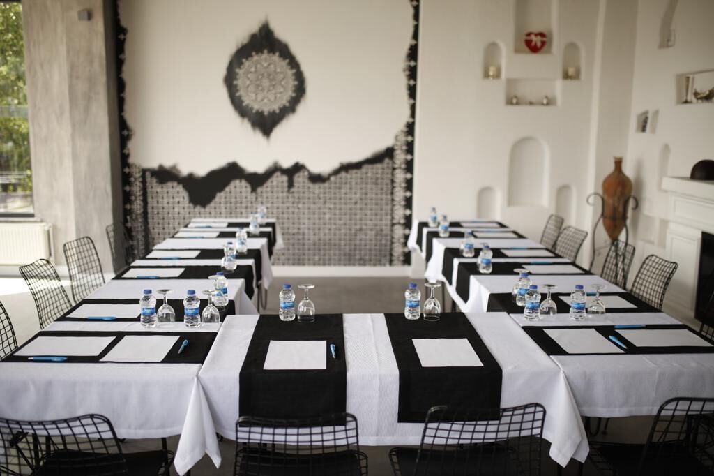 Un salón de conferencias con mesas dispuestas para reuniones, equipado con botellas de agua y bolígrafos.