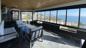 A sunlit balcony with a view of the sea and cityscape. - No57 Suites (Sinop)