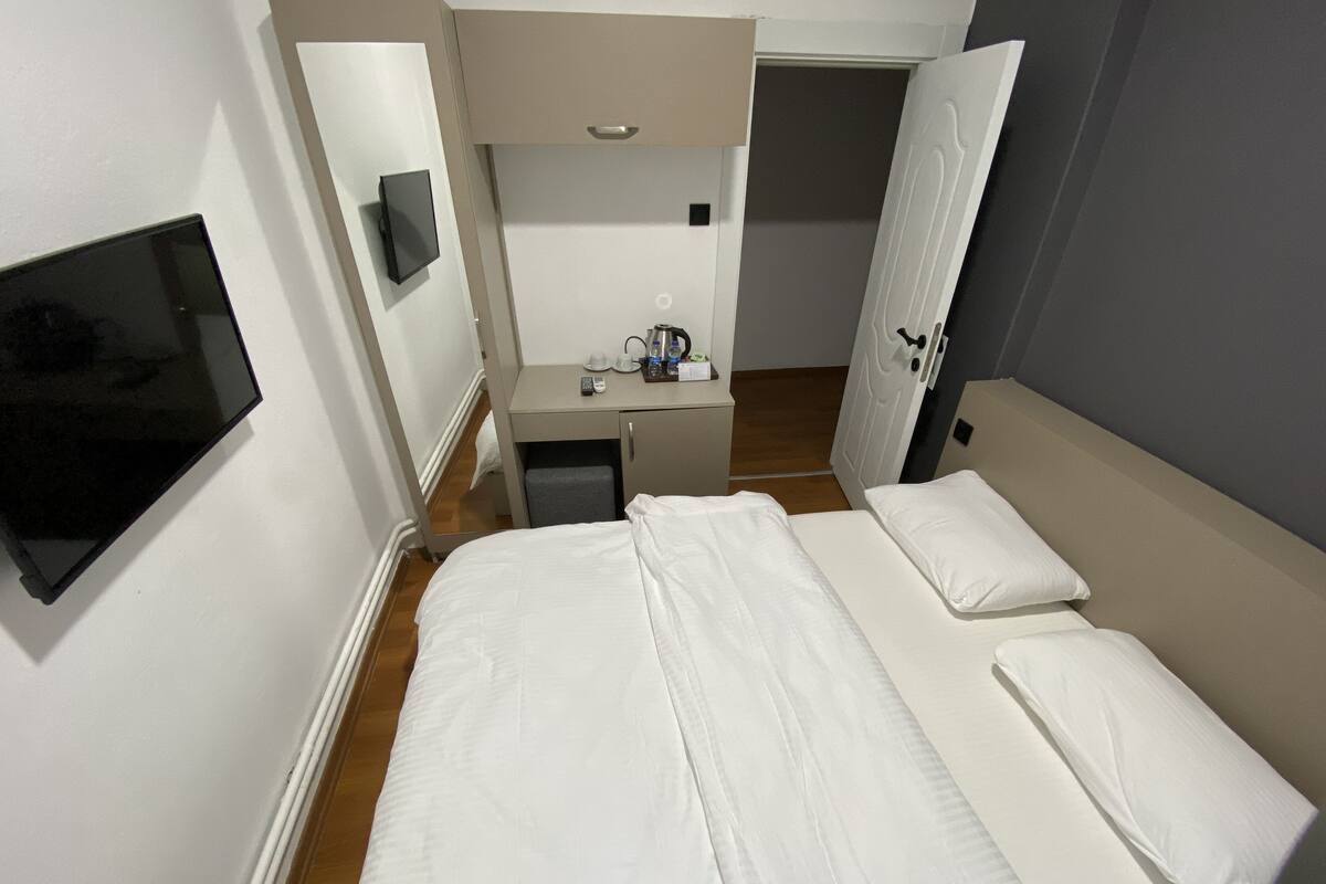 Una habitación de hotel con cama, escritorio, televisión y puerta.