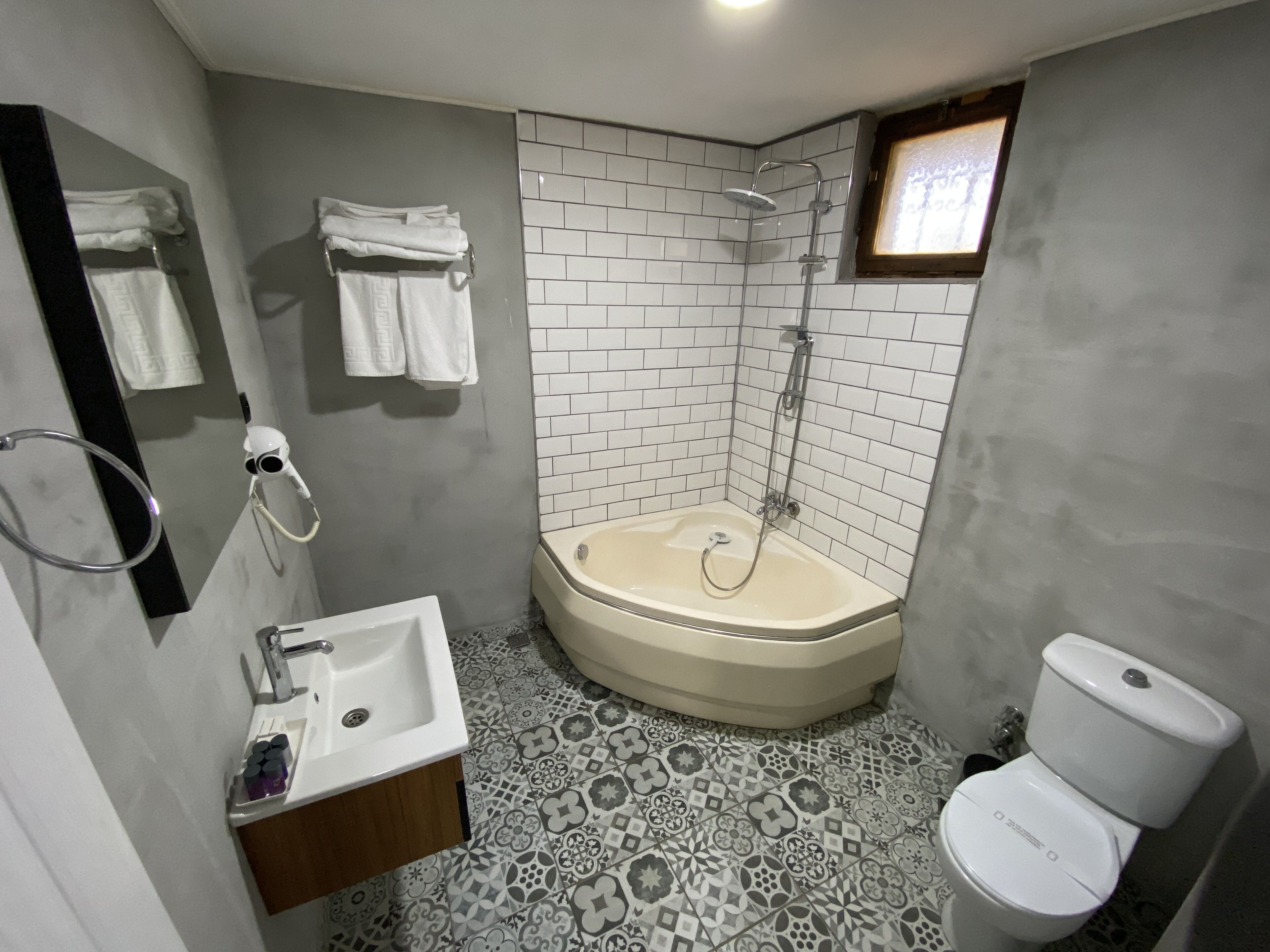 Un baño con ducha, inodoro, lavamanos y espejo.