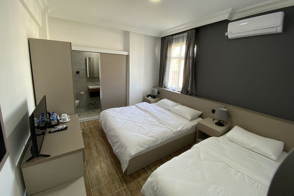Habitación de hotel con dos camas, un escritorio con computadora, televisión y aire acondicionado.