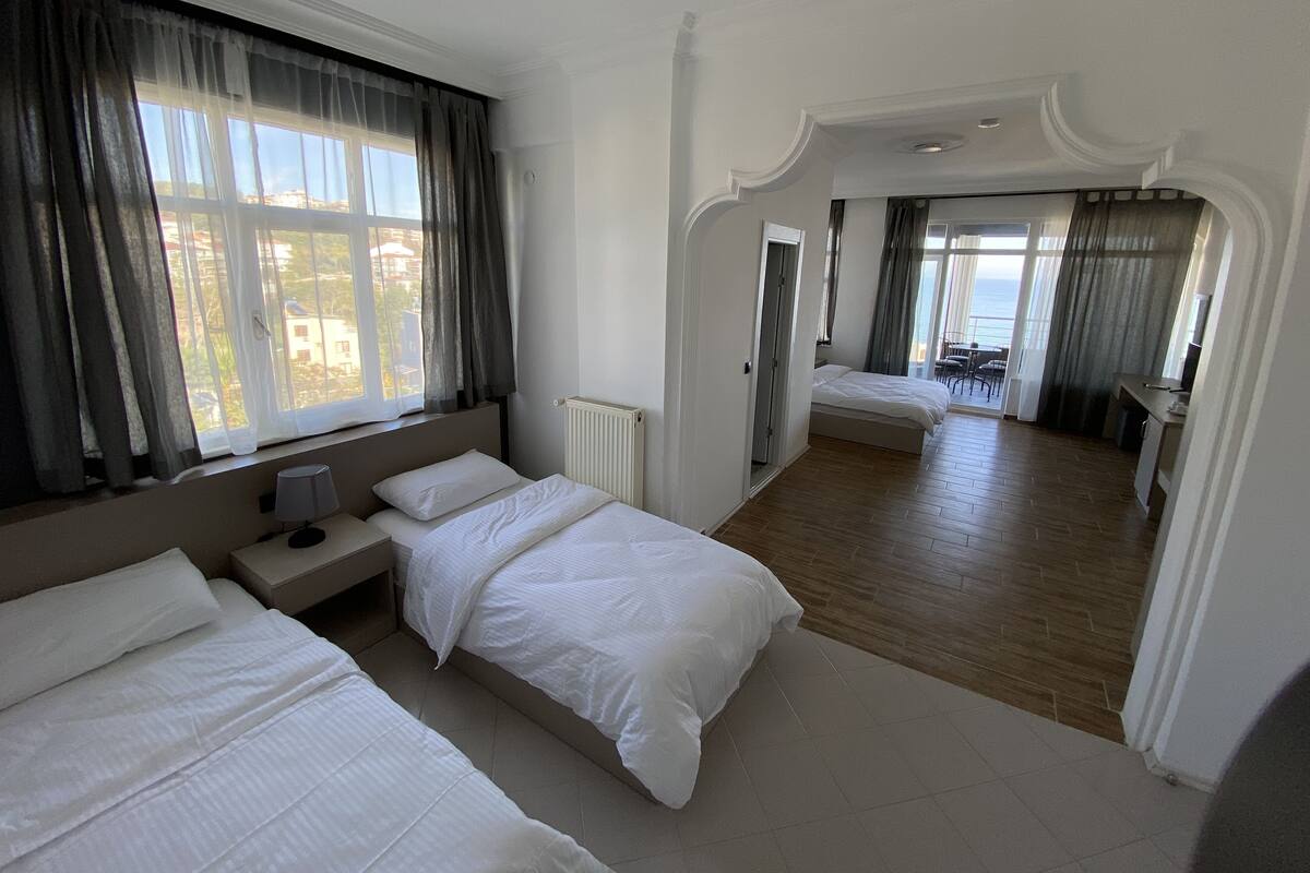 Habitación de hotel con dos camas, vista al mar y un balcón.