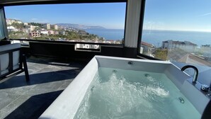 A balcony with a hot tub overlooking a coastal cityscape. - No57 Suites (Sinop)