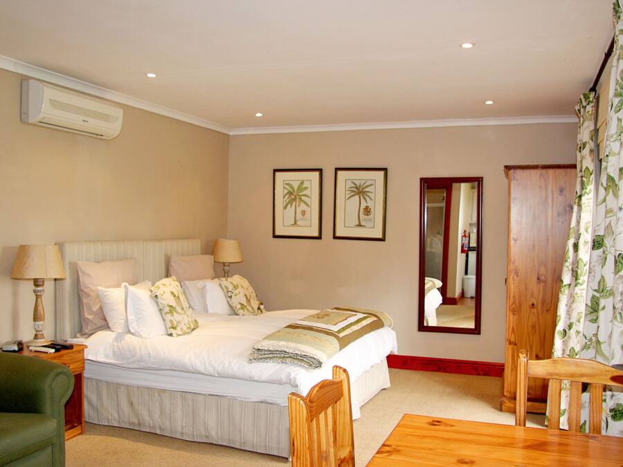 A neatly arranged bedroom with a bed, bedside tables, a chair, and a wooden table.