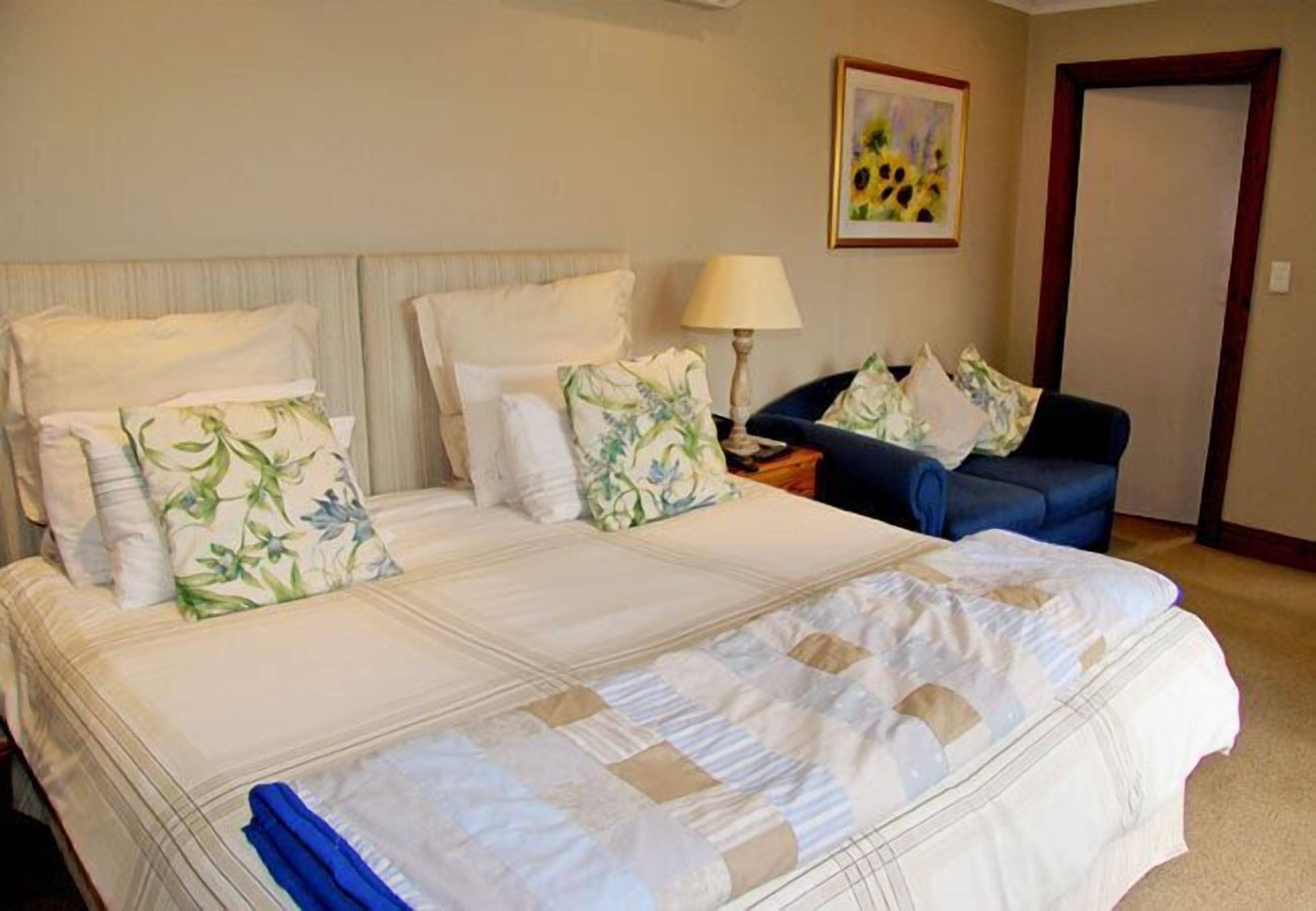 A hotel room with a large bed, two bedside tables, a chair, and a painting on the wall.