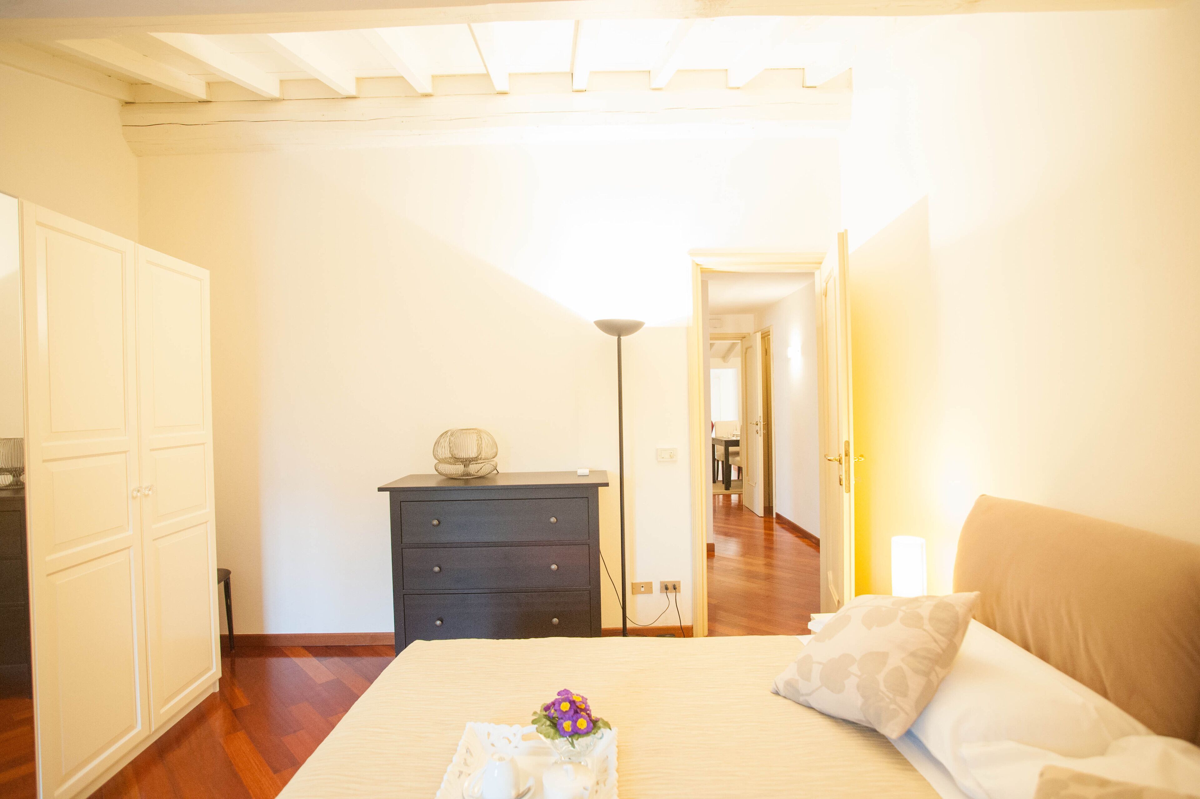 Un dormitorio con cama, cómoda y lámpara.