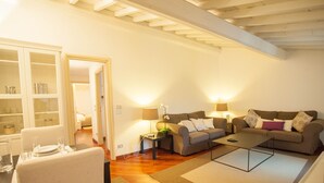 Ein Wohnzimmer mit Sofa, Couchtisch und Essbereich mit Stühlen und einem Tisch für zwei Personen.