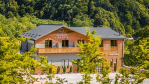 Un hotel con fachada de madera, un balcón y vistas a una ladera boscosa.