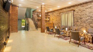 Una habitación amplia con pared de ladrillo, una escalera y una zona de estar con sillas y mesas.