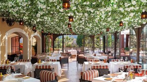 Een restaurant met gedekte tafels, omringd door bogen en een groen begroeid plafond.