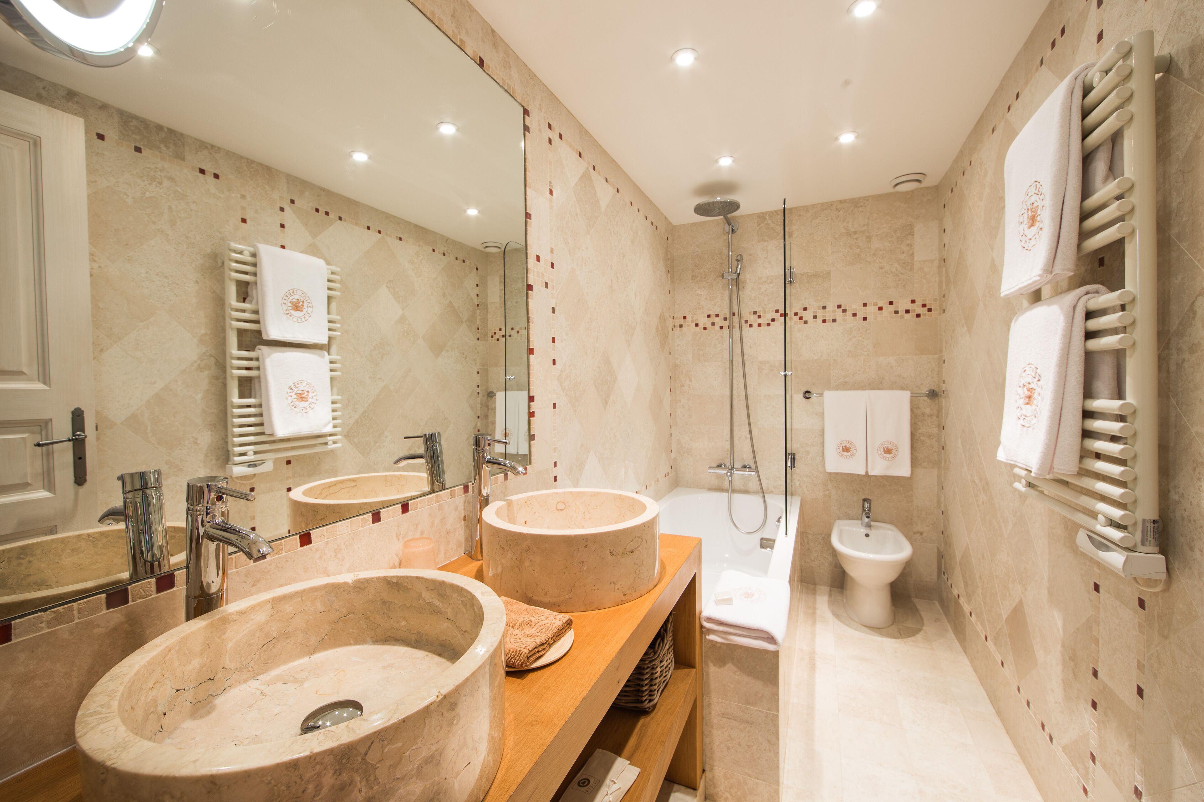 Un baño moderno con dos lavamanos grandes, una bañera y una ducha.